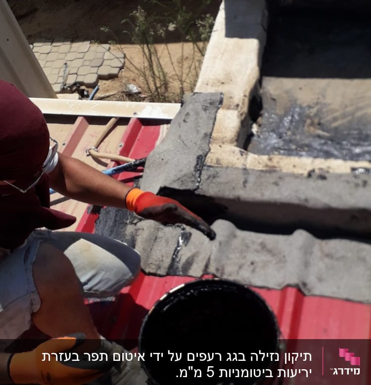 אדם מורח חומר איטום על גג עם מברשת